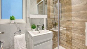 Une salle de bain moderne avec une douche à parois de verre, un meuble-lavabo blanc et un miroir au-dessus du lavabo.