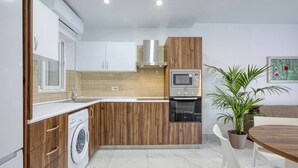 Une cuisine moderne dotée d’appareils électroménagers intégrés, d’un lave-linge et d’un coin repas avec une table et des chaises.