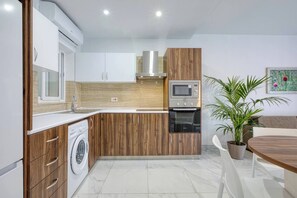 Eine moderne Küche mit integrierten Geräten, einer Waschmaschine und einem Essbereich mit Tisch und Stühlen.