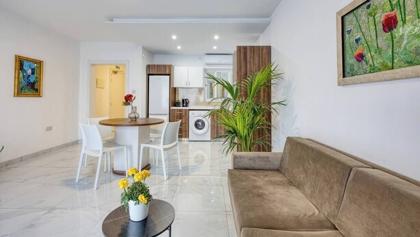 Un salon moderne comprenant un canapé, une table à manger avec des chaises, un coin cuisine et une grande fenêtre.