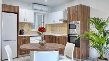 A modern kitchen with wooden cabinets, a built-in oven, and a dining area with a round table and chairs.