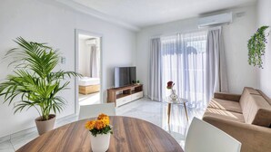 Una sala moderna con televisor, sofá y una mesa de comedor con flores.
