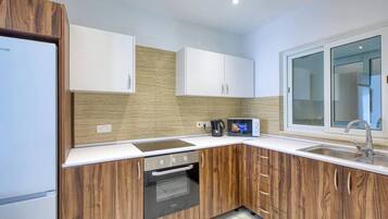 Een moderne keuken met houten kastjes, een ingebouwde oven, een magnetron en een raam boven de spoelbak.
