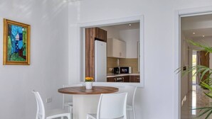 Un comedor moderno con una mesa redonda, sillas blancas y un jarrón de flores.