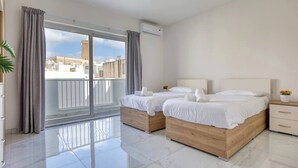 Ett hotellrum med två sängar, en balkong och utsikt över byggnader.