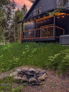 Ett modernt hus med en terrass, omgivet av tät skog.