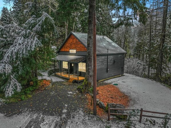 Eine Hütte mit Veranda, umgeben von schneebedeckten Bäumen.