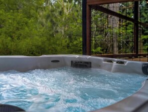 Ein Whirlpool mit Metallgestell und Blick auf grüne Vegetation im Hintergrund.