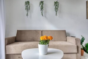 A living room with a beige sofa, a white coffee table with a potted plant, and hanging greenery on the wall. - Modern, Central 3-BR Apt with Valletta View (Tal-Pietà)