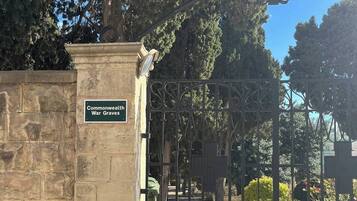 A wrought iron gate with a stone wall and a sign that reads 'Commonwealth War Graves.'