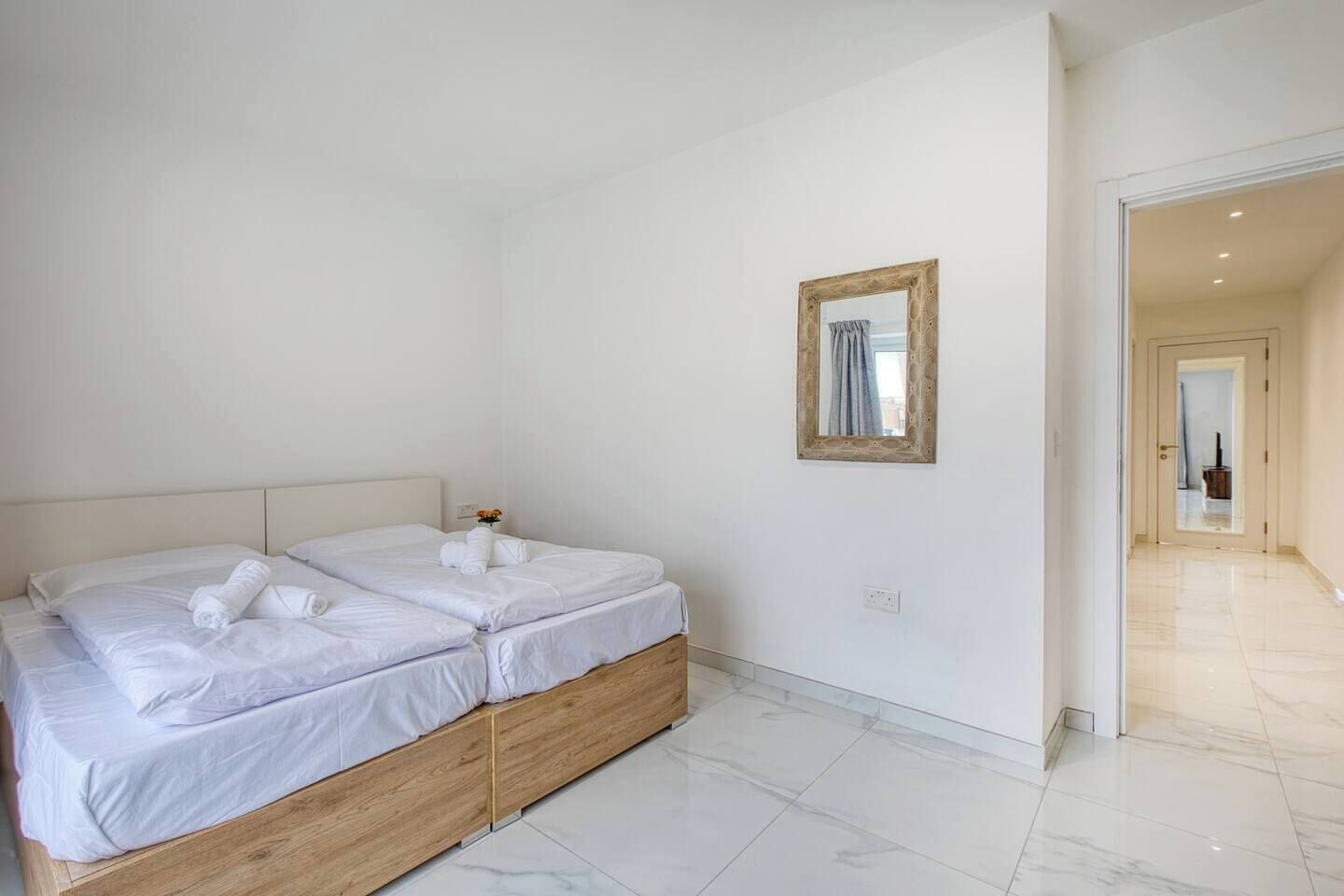 A hotel room with two beds, a wooden headboard, a mirror, and a tiled floor.
