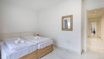 A hotel room with two beds, a wooden headboard, a mirror, and a tiled floor.