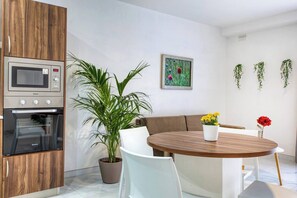 A modern kitchen with built-in appliances, a dining area with a round table, and a potted plant. - Modern, Central 2-BR Apt with Valletta View (Tal-Pietà)