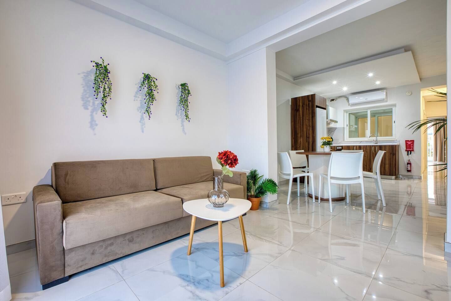 A modern living room with a sofa, a coffee table, and a dining area with chairs and a table.