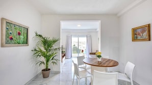 Un intérieur moderne avec un coin repas, une plante en pot et des œuvres d’art accrochées aux murs.