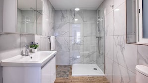 Une salle de bain moderne avec une douche à parois de verre, un lavabo blanc et un plancher en bois.