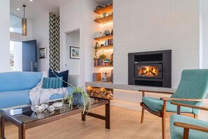Ein modernes Wohnzimmer mit Kamin, einem blauen Sofa, einem grünen Sessel und einem Couchtisch mit Dekoration.