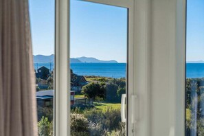 A view through a window with a coastal landscape, including houses and greenery.