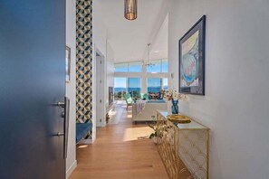 A modern interior with a hallway leading to a seating area with a view.
