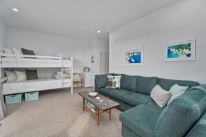 Ein Zimmer mit einem Etagenbett, einem grünen Sofa, einem Couchtisch und zwei gerahmten Bildern an der Wand.