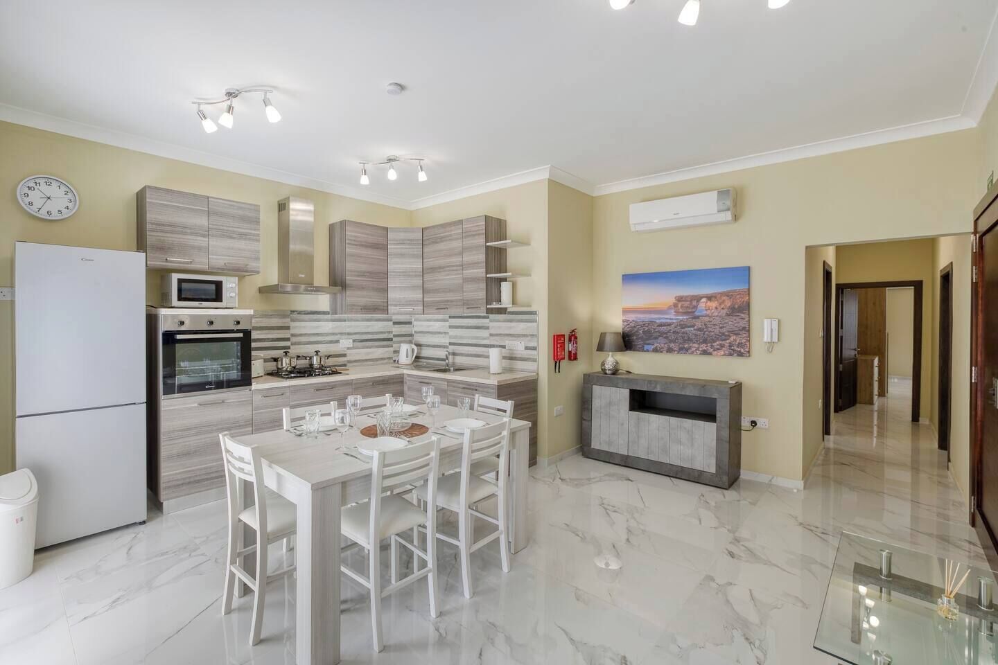 Una cucina moderna con zona pranzo, dotata di frigorifero, forno, microonde e un'isola grande con sedie.