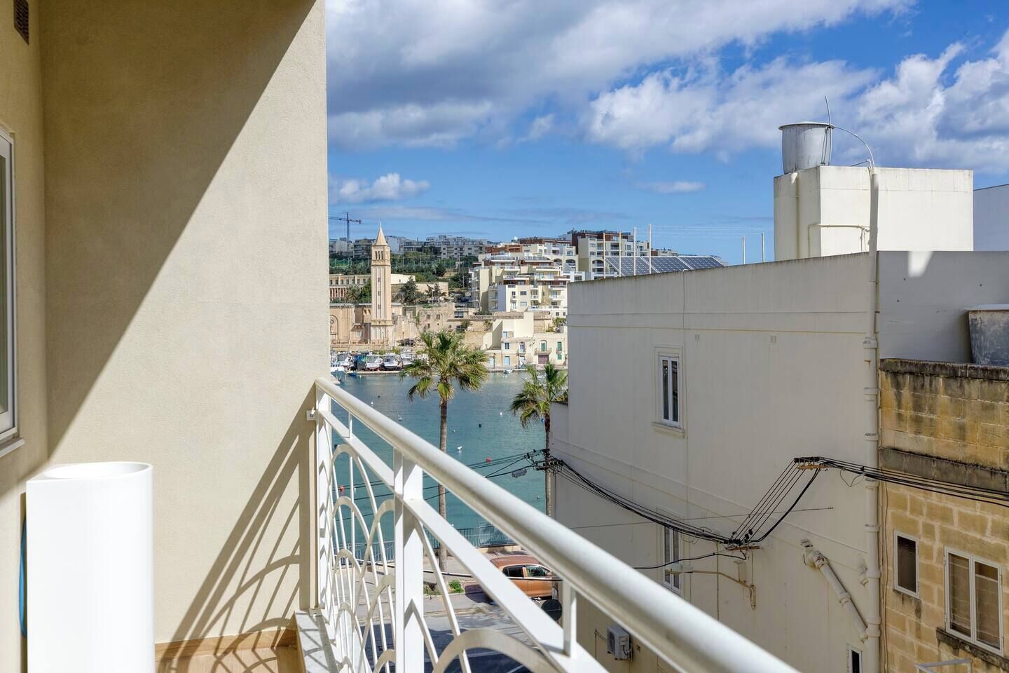 A balcony with a view of a coastal town, including buildings and a tower.