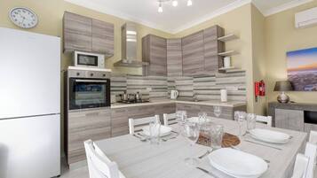 A modern kitchen with a built-in oven, microwave, and gas stove. There is a dining table set with plates, glasses, and cutlery.