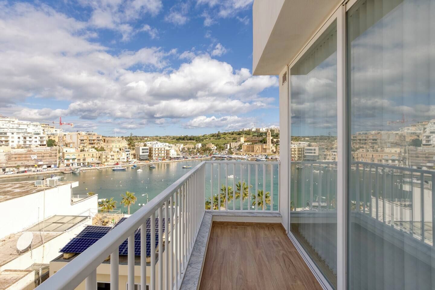 Un balcón con vista a un puerto deportivo y al paisaje urbano.