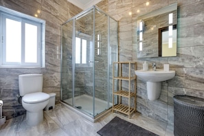 Ein modernes Badezimmer mit Duschkabine, Toilette, Waschbecken und Spiegel.