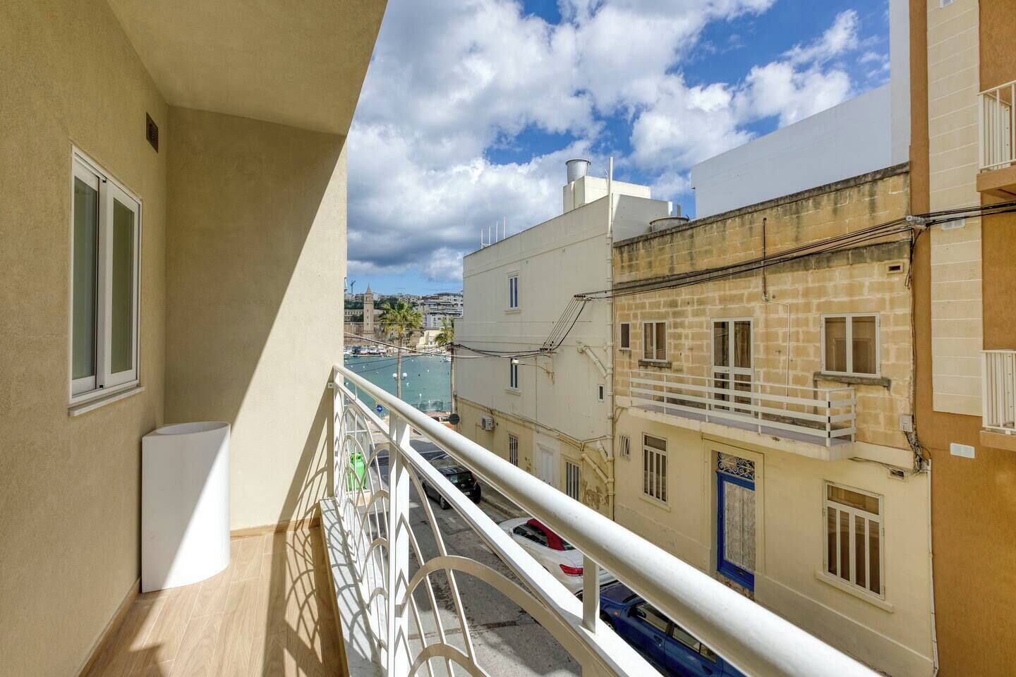 Un balcon donnant sur une zone côtière, des bâtiments dotés de balcons et un ciel dégagé.