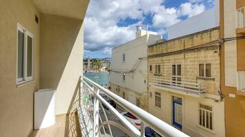 Un balcon donnant sur une zone côtière, des bâtiments dotés de balcons et un ciel dégagé.