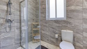 Ein modernes Badezimmer mit einer Duschkabine, einer Toilette und einem Fenster.