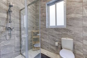Une salle de bain moderne avec une douche à parois de verre, des toilettes et une fenêtre.