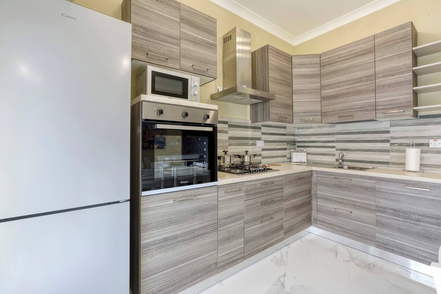 A modern kitchen with a built-in oven, microwave, and gas stove.