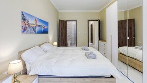 Un dormitorio con una cama, mesitas de noche, un espejo y un cuadro en la pared.