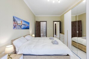 Un dormitorio con una cama, mesitas de noche, un espejo y un cuadro en la pared.