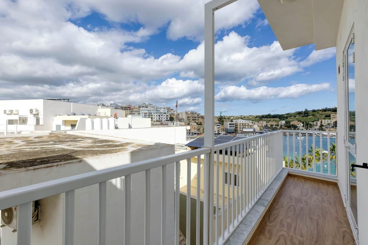 A balcony with a view of a marina and buildings in the distance.