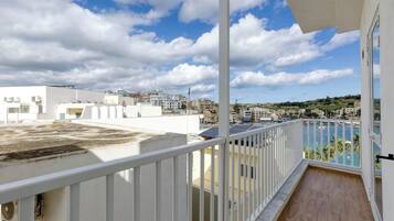 A balcony with a view of a marina and buildings in the distance.