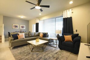 A living room with a sofa, a coffee table, and a TV stand. - SeaWorld 5-bedroom townhome with Pool in Orlando (Kissimmee)