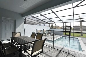 A covered patio area with a pool, outdoor seating, and a view of the neighborhood. - SeaWorld 5-bedroom townhome with Pool in Orlando (Kissimmee)