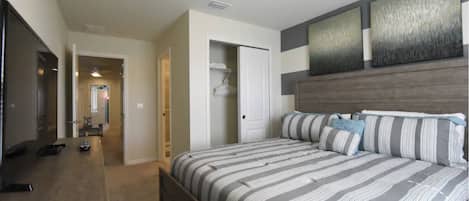 Une chambre à coucher avec un grand lit, une armoire, un miroir et un téléviseur.