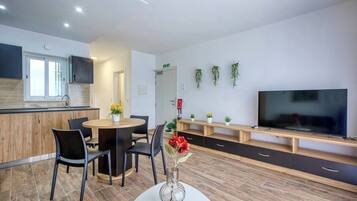 A modern kitchen with a dining area, a TV, and a plant wall.