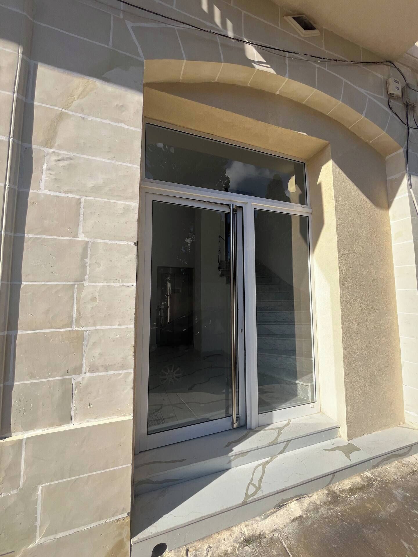 A building entrance with a glass door and a stone facade.