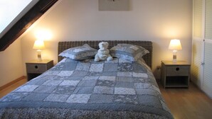 A bedroom with a bed, pillows, a teddy bear, two bedside lamps, and a wall clock. - Le Bretzel Apartment with Mountain View and Wi-Fi (Ribeauvillé)