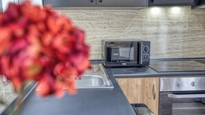 Een moderne keuken met een inbouwmagnetron, roestvrijstalen apparatuur en een houten aanrecht.