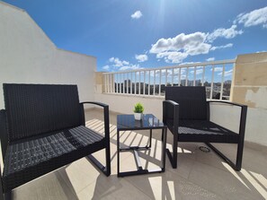 A rooftop terrace with two black wicker chairs, a small table, and a potted plant. - Modern, Central 1BR Penthouse – Valletta View (Tal-Pietà)