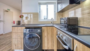 Een moderne keuken met een ingebouwde wasmachine, een magnetron en een kookplaat.