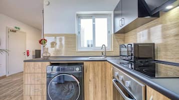 A modern kitchen with a built-in washing machine, a microwave, and a stovetop.