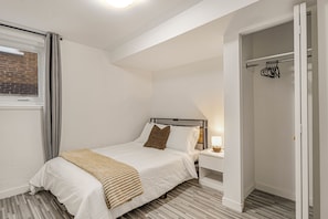 A bedroom with a bed, bedside table, and a wardrobe.