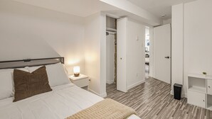 Un dormitorio con cama, mesita de noche, lámpara y armario.